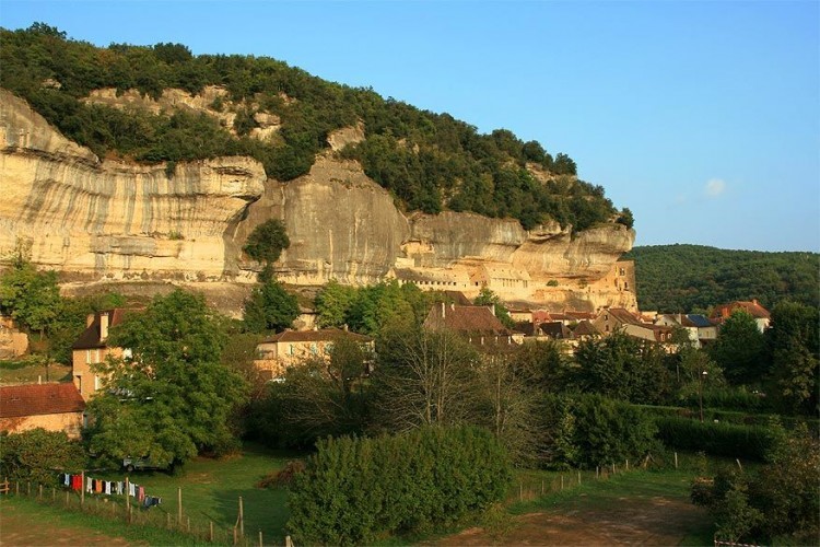 Les Eyzies-de-Tayac-Sireuil, Frankrijk: met gevels die in de rotswand gemetseld zijn, lijkt dit stadje precies onbereikbaar en onbezocht. Maar niets is minder waar. Les Eyzies-de-Tayac-Sireuil kreeg de bijnaam van prehistorische hoofdstad omdat er zoveel grotten en abri’s uit die tijd ontdekt zijn. © Wikimedia Commons