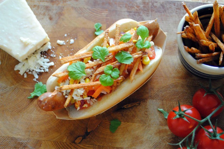 Brazilië: hotdog in een halfopen broodje met pico de gallo, een Mexicaanse saus, mais, geraspte Parmezaanse kaas, geraspte wortelen, plakjes ham, koriander en fijne frietjes (steppegras). © bimbim101