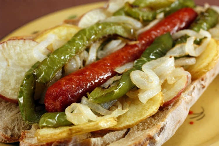 Italië: gefrituurde hotdog in een Italiaans broodje met paprika, ui, frietjes, ketchup en mosterd. © Recipes Hubs