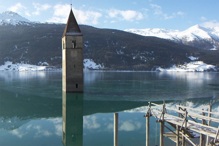 Verdronken kerk in Zuid-Tirol, Italië: de 14de-eeuwse toren van de kerk is het enige wat nog zichtbaar is van het kleine stadje dat in 1950 artificieel werd overspoeld. Wanneer het meer bevriest kan je de toren zelfs te voet bereiken! © Wikimedia Commons